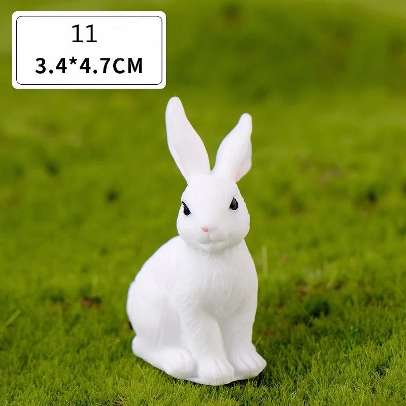 A white miniature rabbit figurine sitting on green grass.