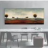 A horizontal painting featuring a landscape of rolling hills under a pale sky, displayed above a white table.