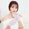 A woman wearing white lace gloves, looking at the camera.