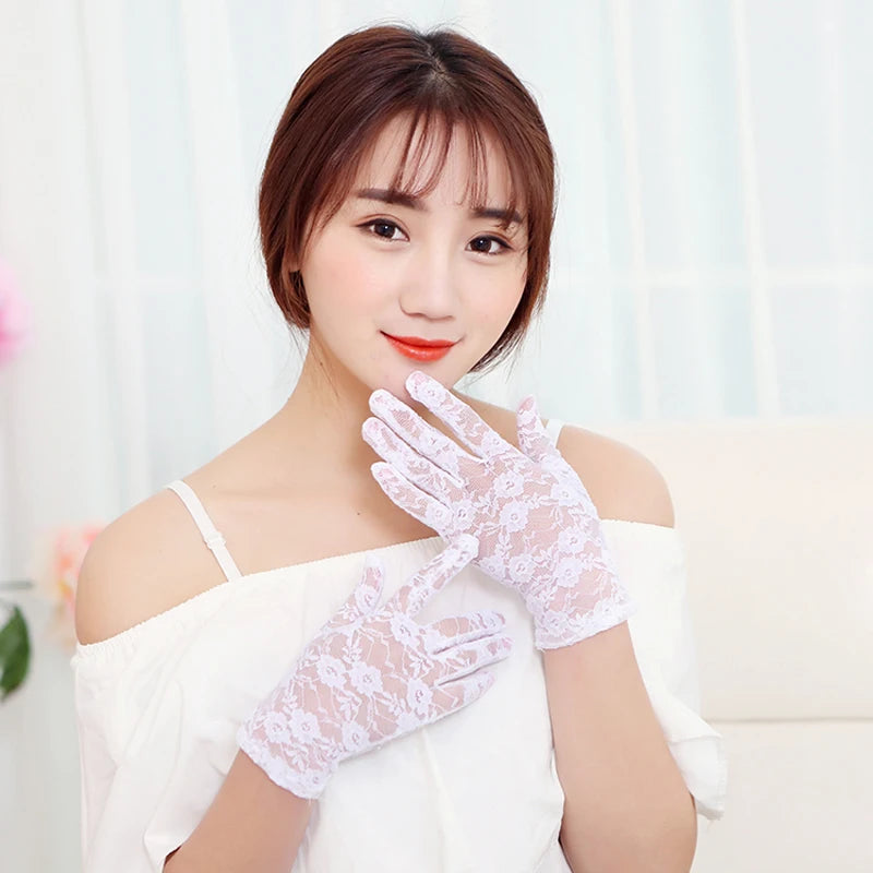 A woman wearing white lace gloves, looking at the camera.