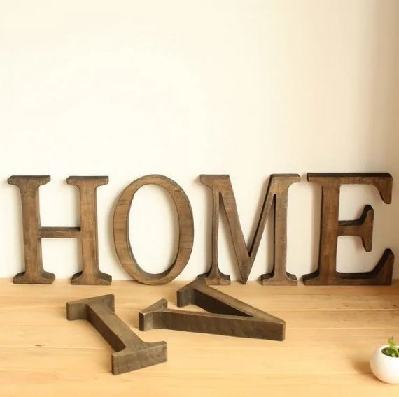 Vintage wooden alphabet letters spelling HOME arranged on a light wooden surface.