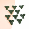 A collection of small, artificial green leaves scattered on a light pink and white background.