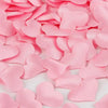 Pink heart-shaped sponge confetti scattered on a white surface for weddings and celebrations