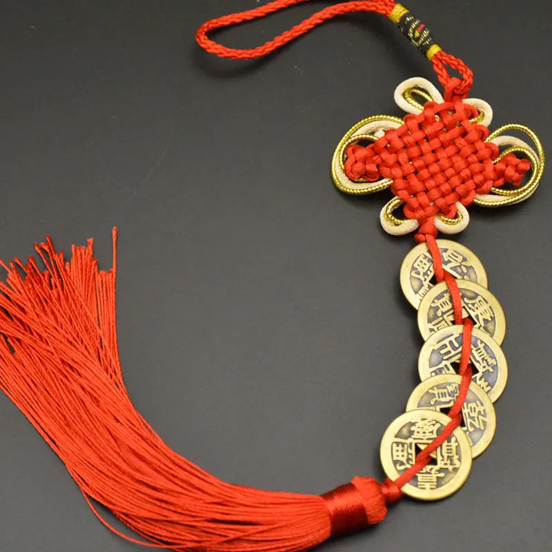 A handwoven knot charm featuring an I Ching copper coin and Feng Shui design, tied with a red thread.