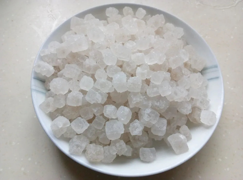 A pile of white natural unrefined sea salt crystals in a white bowl.