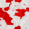 Red and white heart-shaped sponge confetti scattered on a white surface.