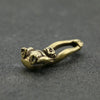 Vintage brass monkey key chain charm with a loop, resting on a dark gray surface.