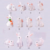 Twelve miniature white rabbit figurines arranged in a grid display.