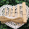 A set of natural wooden clips used for crafts, photos, and decor, laid on a white lace doily.