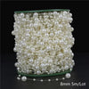 A spool of ivory pearl beads used for garland decoration, with a string of beads visible below.