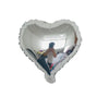Eine Person ist in einem großen herzförmigen Aluminiumfolienballon und schaut durch die transparente Oberfläche.
