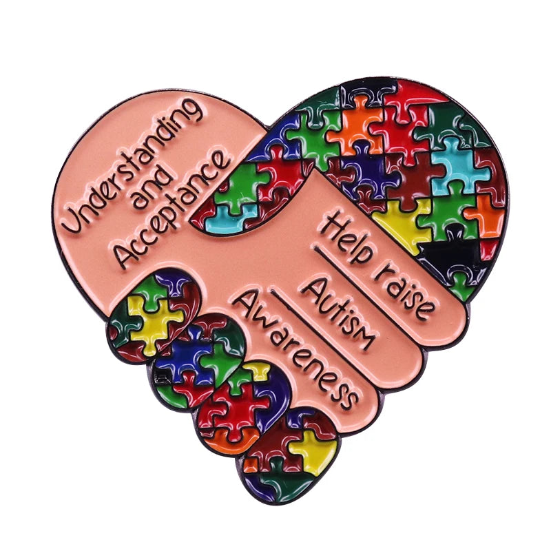 A heart-shaped pin featuring a puzzle piece design with text about understanding and acceptance, help raise autism awareness,