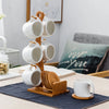 A ceramic coffee mug set with white mugs and a bamboo wood stand displayed on a table.