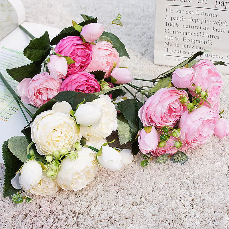 A bouquet of pink and white silk rose and peony artificial flowers with green leaves