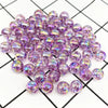 A pile of iridescent purple acrylic round beads for jewelry making scattered on a grid background.