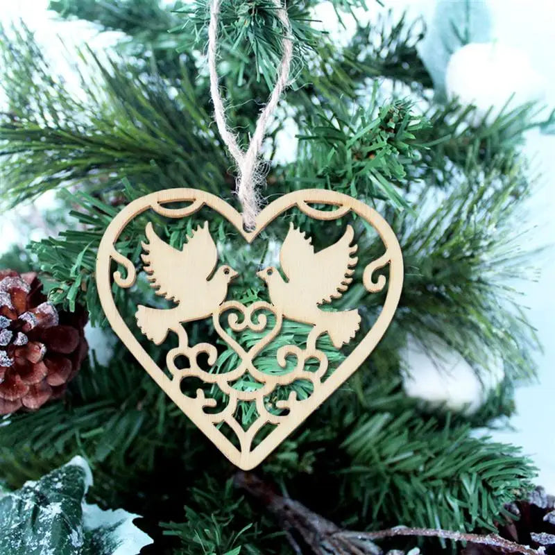 A wooden heart-shaped ornament featuring two birds carved into the design, hanging on a green pine branch.