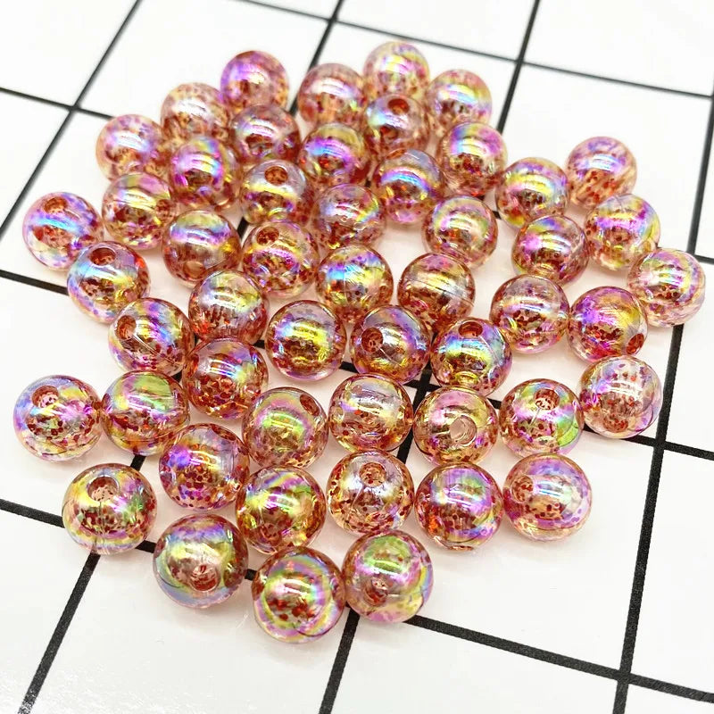 A pile of small, round, iridescent pink and gold acrylic beads for jewelry making