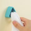 A hand is holding a white towel and placing it onto a light blue suction cup towel holder mounted on a wall.