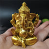 A golden Ganesha statue handcrafted from resin held in a person's hand.