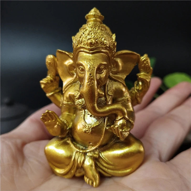 A golden Ganesha statue handcrafted from resin held in a person's hand.