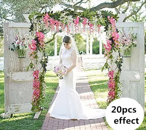 A white wedding arch decorated with pink and green floral vines and greenery for outdoor events