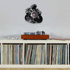 A motorcycle rider vinyl record wall clock mounted on a light gray wall above a wooden shelf displaying vinyl records.