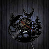 A black silhouette of a woodland elk deer head is cut into a round clock face with a dark background.