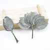 A set of twelve silk leaf artificial plant stems with vases displayed on a wooden board.