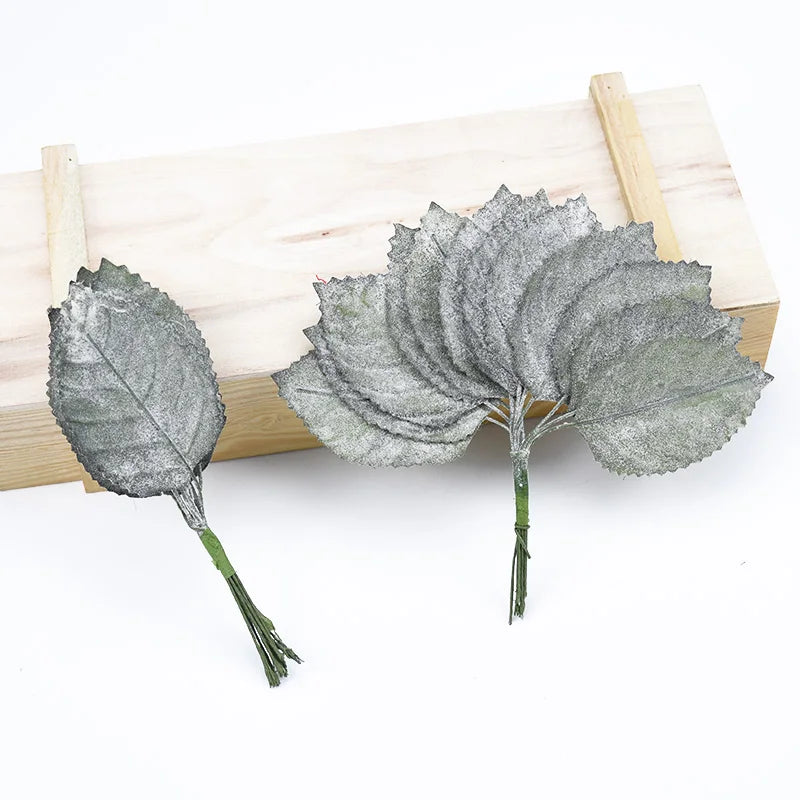 A set of twelve silk leaf artificial plant stems with vases displayed on a wooden board.