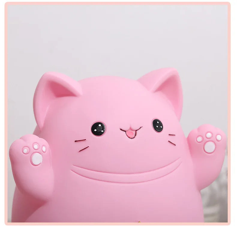 A pink cartoon cat figure designed as a piggy bank for saving money, featuring cute facial expressions and paw hands.