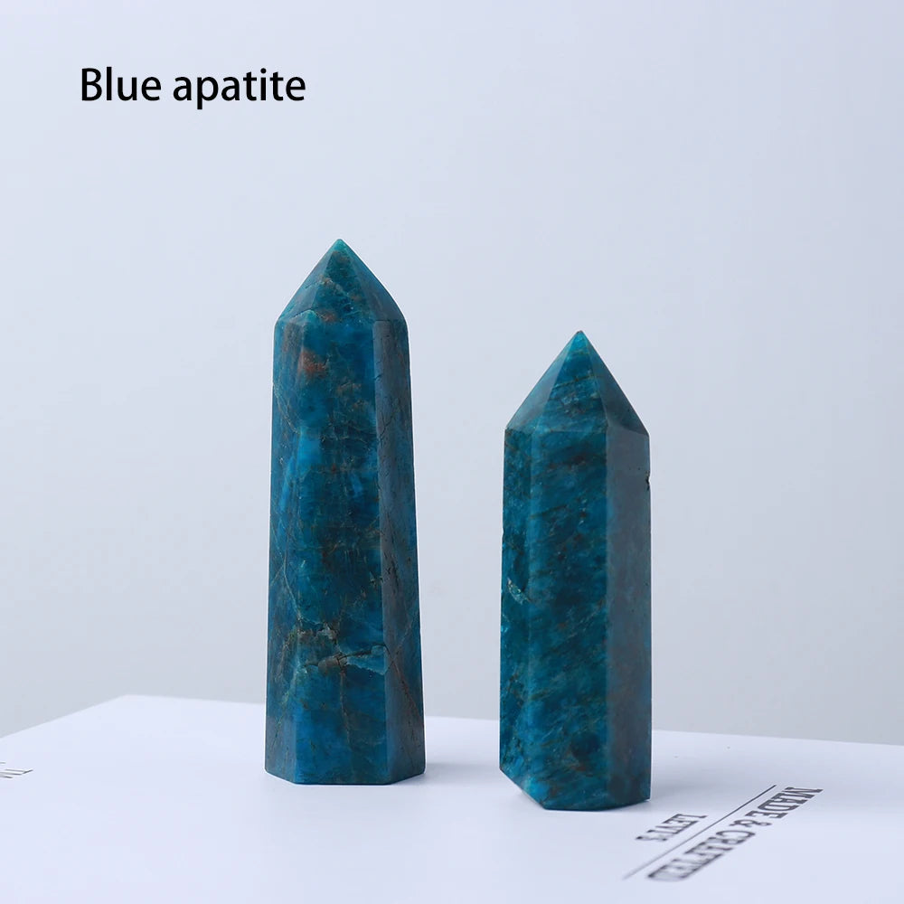 Two deep blue apatite crystal point prisms displayed on a white surface.