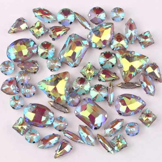 A mix of iridescent silver claw setting glass rhinestones in jelly candy AB colors scattered on a white background.