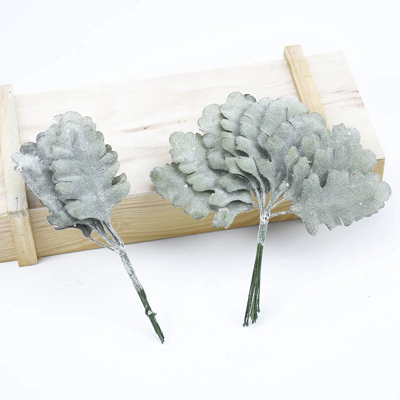 A set of twelve silk leaf artificial plant stems with vases displayed on a wooden board.
