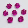 A collection of faceted pink and magenta acrylic crystals used as party decorations.