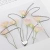 Silver titanium steel heart lock key pendant necklace displayed on a white background with pink roses.