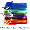 A stack of colorful organza drawstring gift pouches in various shades of blue, green, purple, and orange.
