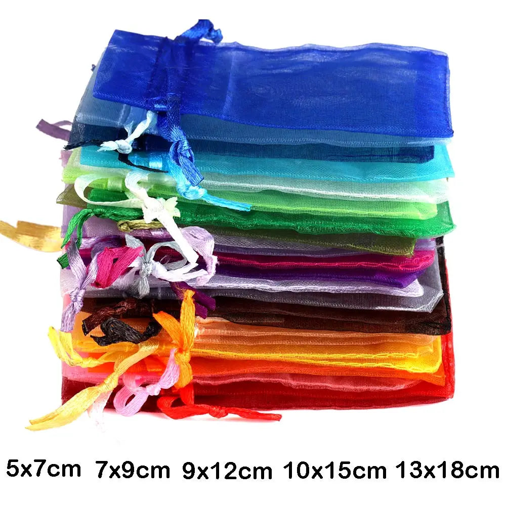 A stack of colorful organza drawstring gift pouches in various shades of blue, green, purple, and orange.