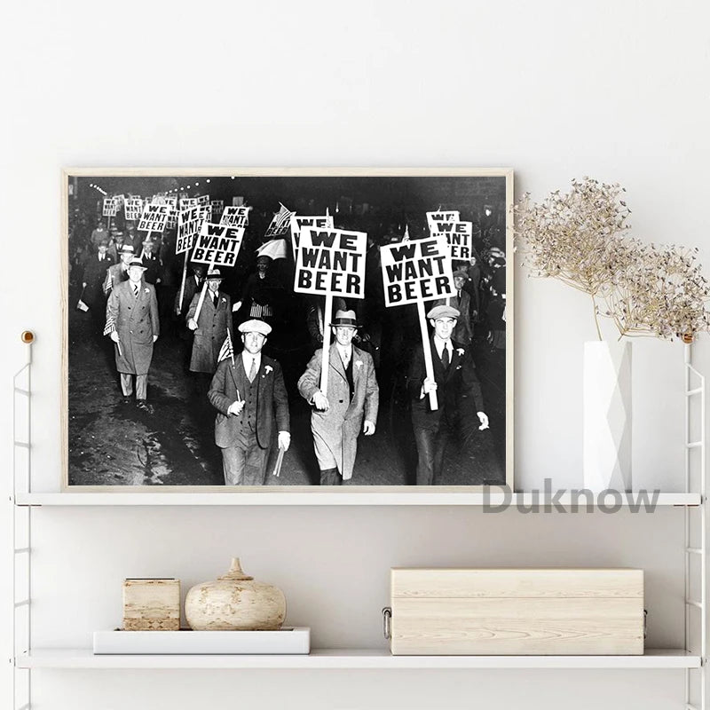 Black and white print of a vintage Prohibition-era beer sign featuring several men holding signs that read We Want Beer