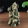 Bronze Hanuman statue figurine of a monkey god seated in a devotional pose on a wooden surface.