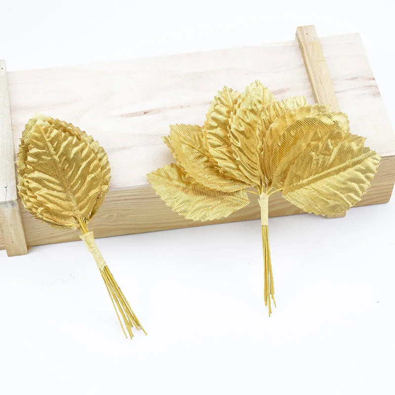 A set of twelve gold silk leaf artificial plant stems with vases displayed on a wooden board.