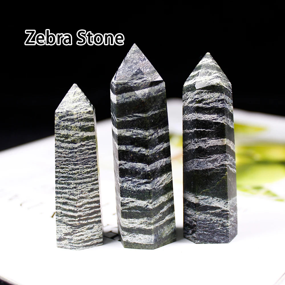 Three ZEBRA STONE crystal points displayed on a white surface.