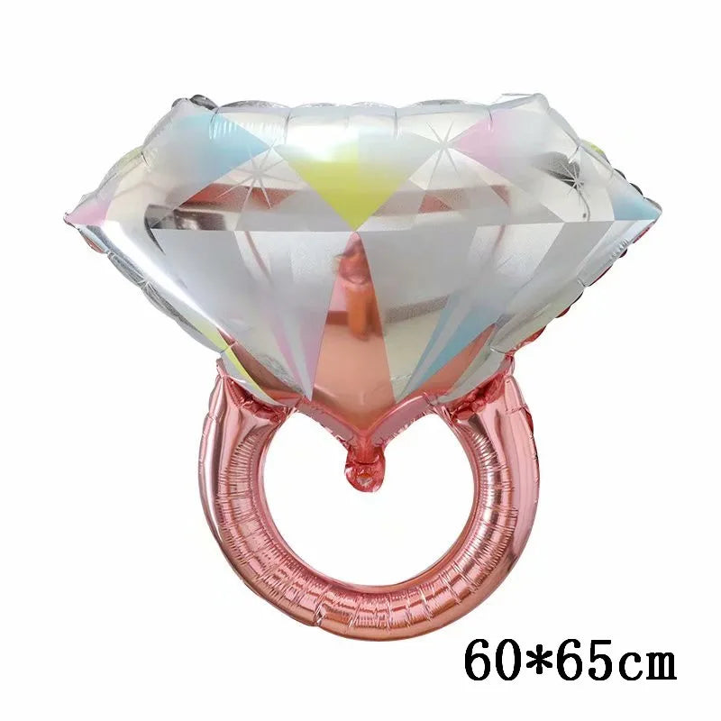 Anillo de acrílico facetado en forma de diamante con acabado rosa y globo de papel brillante adjunto.