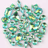 A mix of silver claw setting glass rhinestones in jelly candy AB colors scattered on a white background.