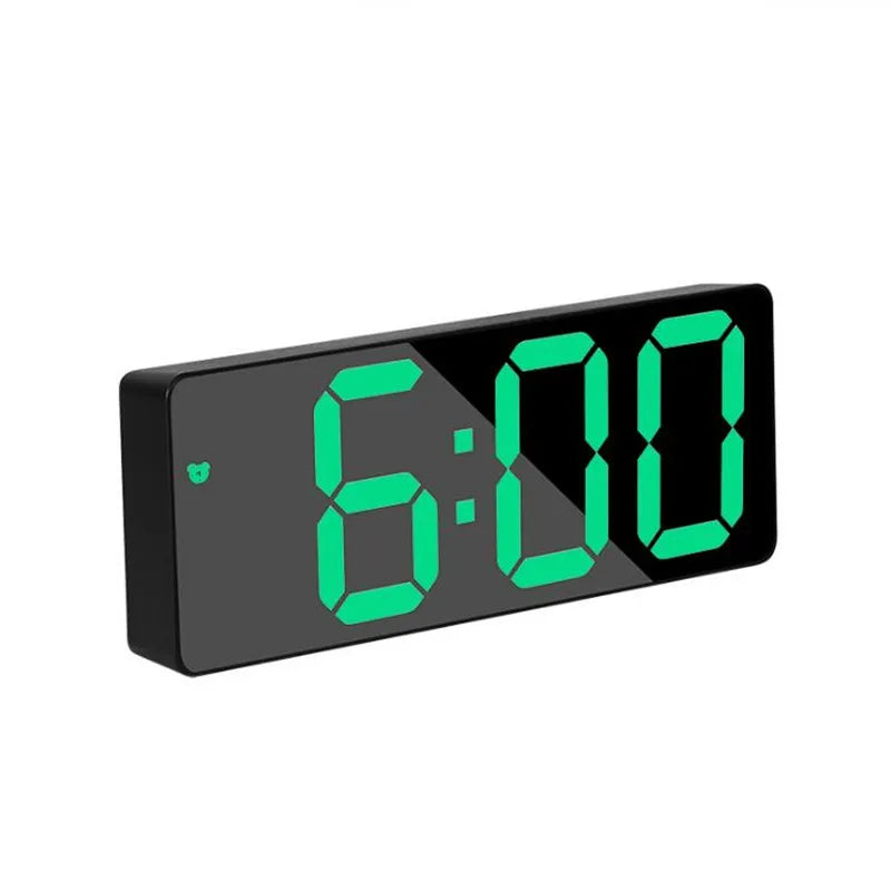 A black digital alarm clock displaying the time 6:00 in bright green LED digits.