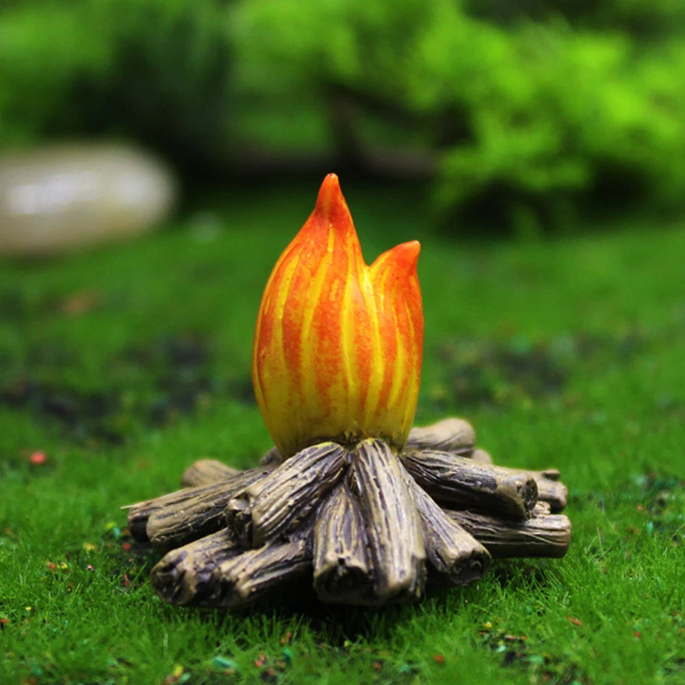 A miniature resin gnome statue with an orange and yellow flower-like top rests on a bed of moss and small twigs in green gras