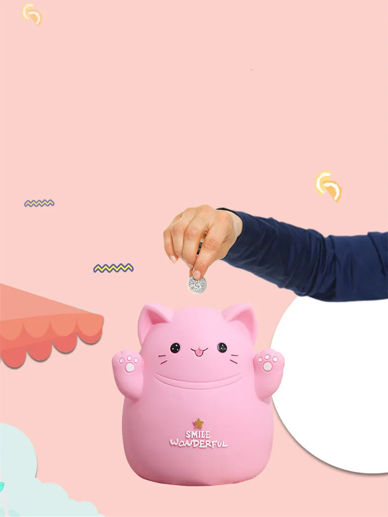 A pink cartoon cat piggy bank is being held by a hand against a light pink background.