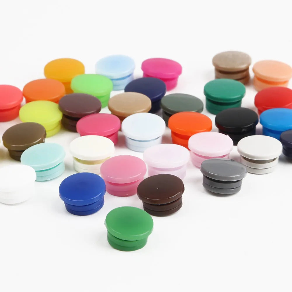 Assorted snap buttons in various colors including orange, pink, green, and brown, arranged on a white background.