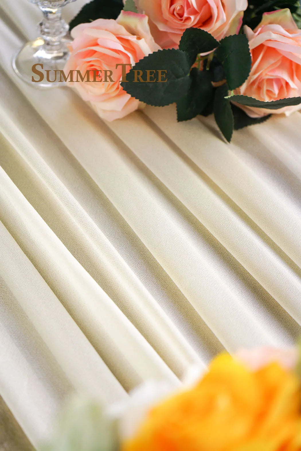 A close-up of soft peach roses and green leaves arranged on a cream fabric background.