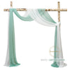 White and greyish green chiffon fabric draped over a wooden wedding arch structure.