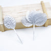 A set of twelve silver silk leaf artificial plant stems with vases displayed on a wooden surface.
